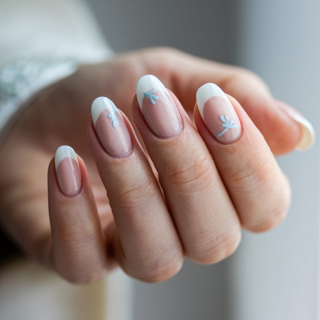 A close-up shot of a woman's hand with five fingers. Each finger has a milky French nail with delicate baby blue accents. The soft pinkish-nude base blends seamlessly into creamy white tips. There are subtle blue details in the form of thin lines or tiny hearts, adding a playful yet chic touch. The hand is posed naturally, with fingers slightly relaxed. The light interacts with the glossy finish, and the soft natural lighting enhances the pastel tones. The background is blurred and neutral, keeping all focus on the delicate yet trendy manicure.