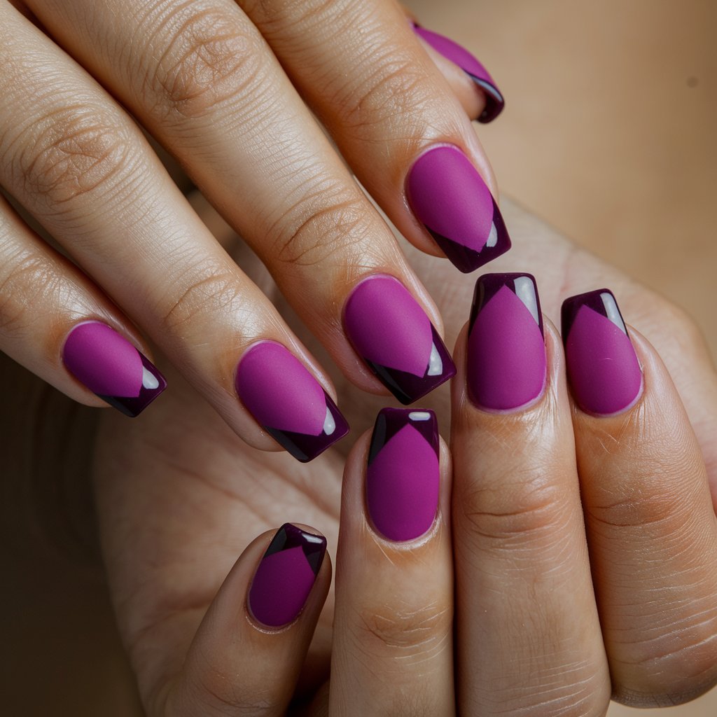 A close-up shot of a well-moisturized woman's hand with five fingers. Each finger has a striking contrast between a matte magenta base and glossy deep purple tips. The nails have a sharp French tip design. The background is natural and enhances the purple and pink nails. The squared-off shape gives a modern and sophisticated edge, while the smooth, nourished skin enhances the bold yet refined look.