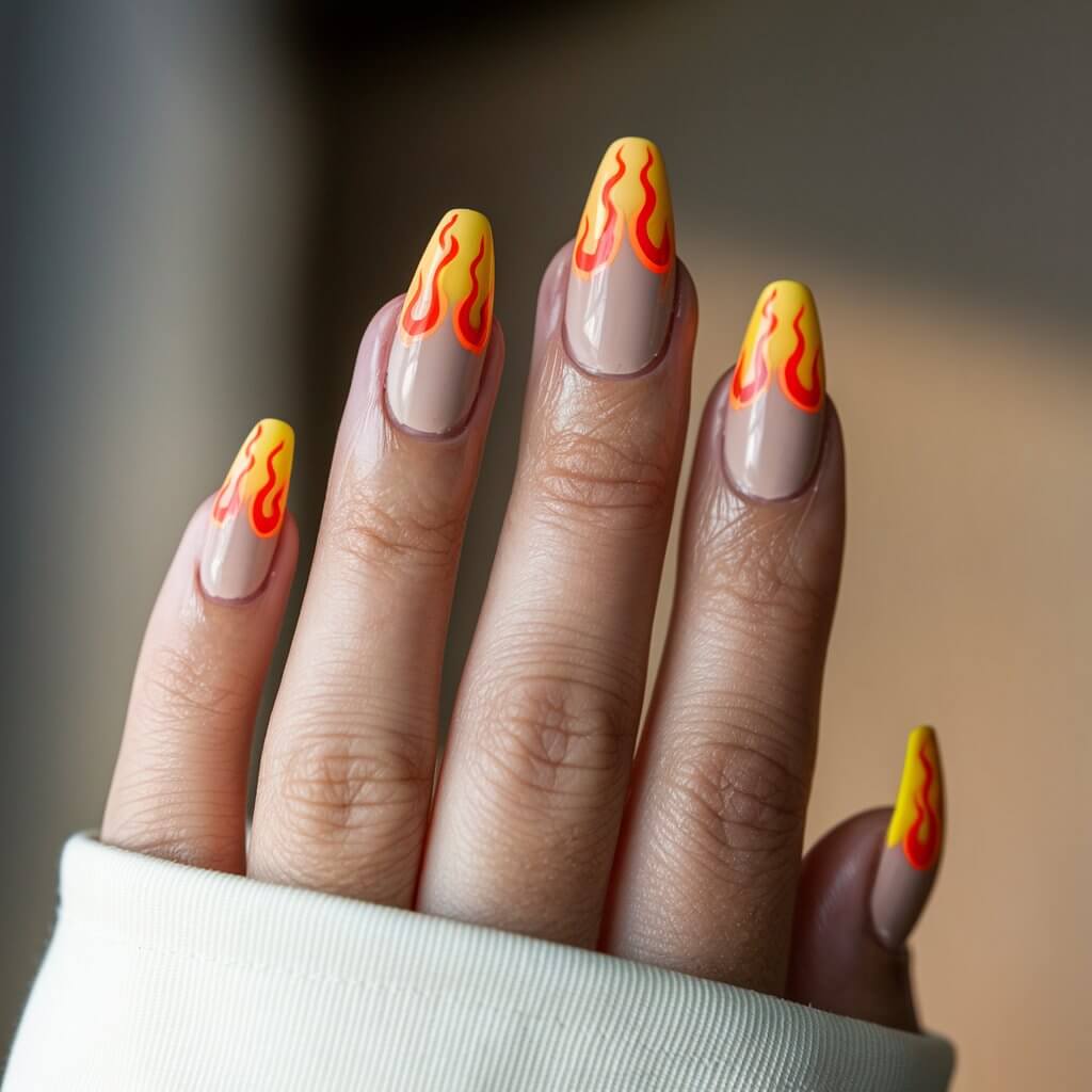 A close-up of a well-moisturized woman's hand presenting five fingers adorned with a striking flame design. The nails have a nude base, with hand-painted neon orange flames licking up from the tips. The glossy finish reflects the natural background lighting, intensifying the fiery effect. The coffin-shaped nails add an edgy appeal, while the fingers are positioned elegantly to showcase the intricate flame detailing. A softly blurred background subtly complements the bold, high-energy manicure, making the flames appear even more dynamic.